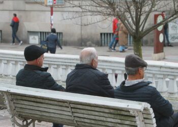 Personas mayores sentadas en un banco en la ciudad de Ourense.