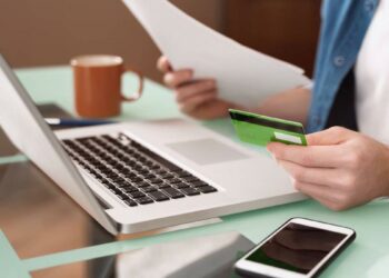 Persona utilizando un teléfono móvil para realizar gestiones bancarias y trámites por internet.